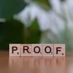 A wooden block spelling proof on top of a table