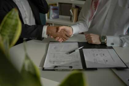 two people shaking hands over a piece of paper