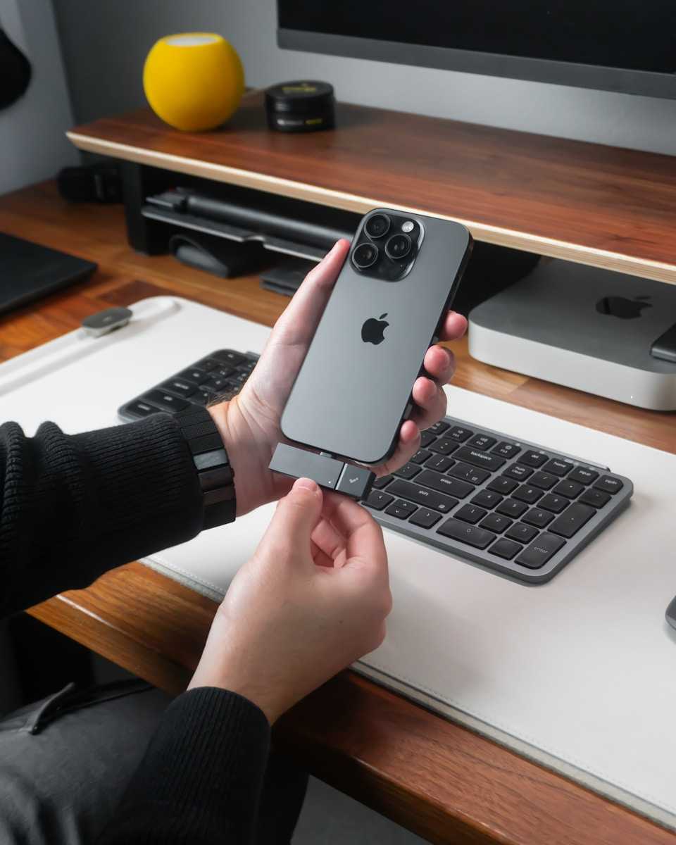 Person attaching accessory to iPhone on desk.