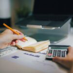 a person sitting at a desk with a calculator and a notebook