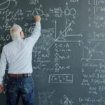 A professor writing complex formulas on a blackboard.