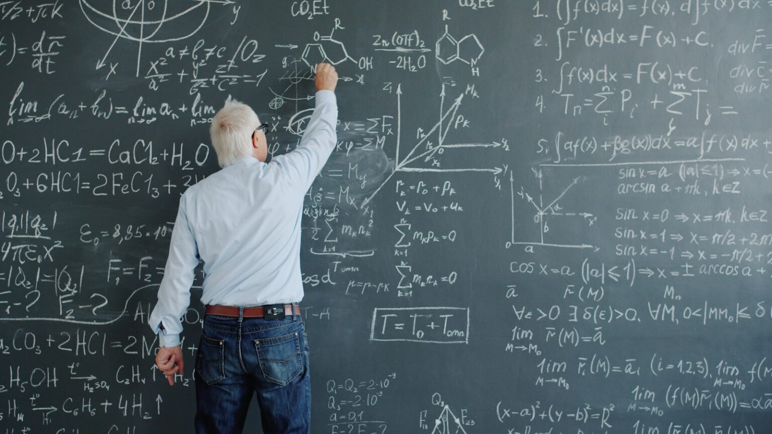 A professor writing complex formulas on a blackboard.