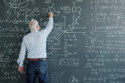 A professor writing complex formulas on a blackboard.