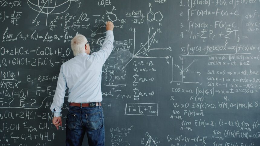 A professor writing complex formulas on a blackboard.