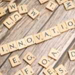 scrabble tiles spelling the word innovation on a wooden surface