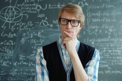 Man with glasses thinking in front of chalkboard